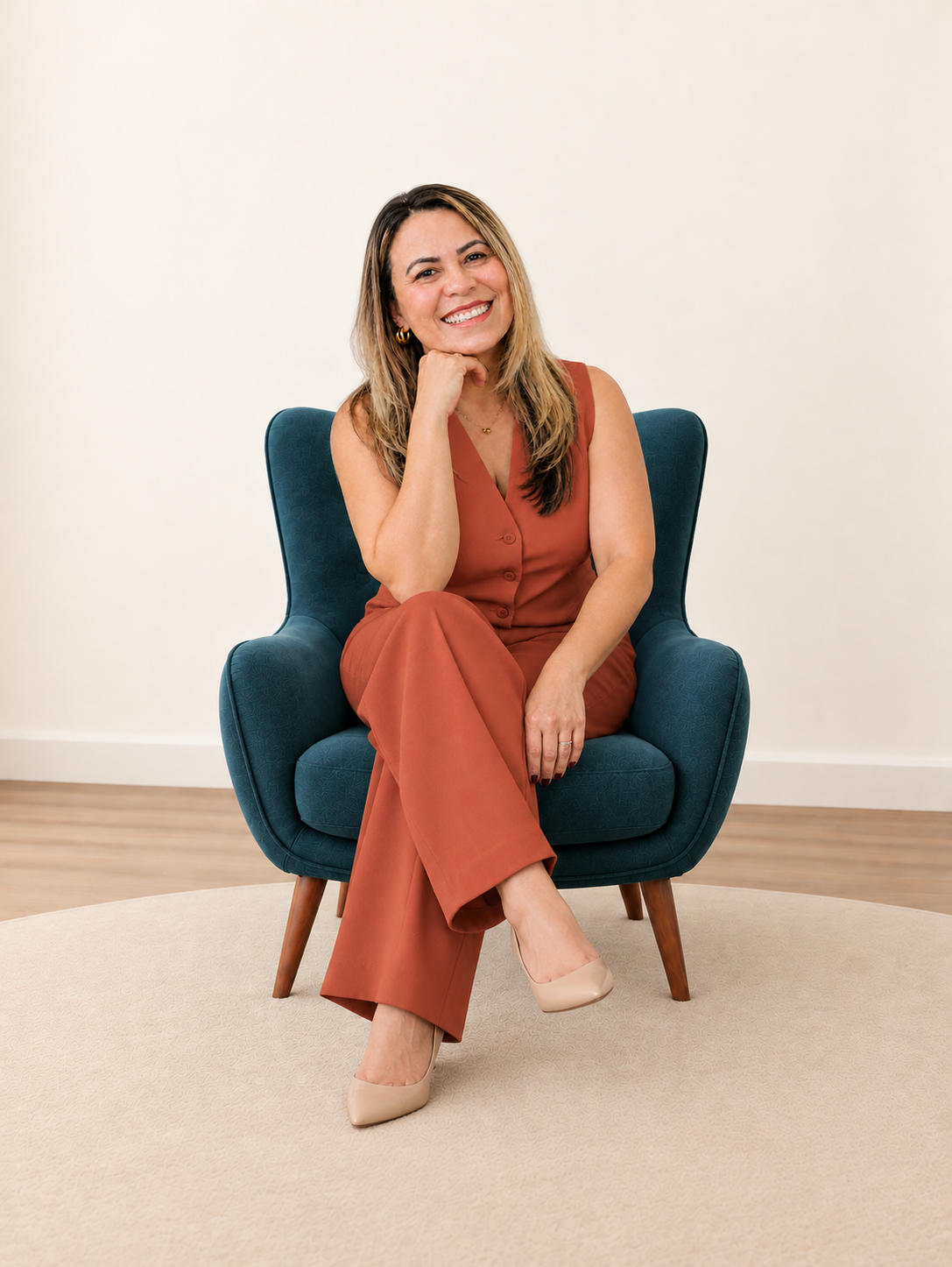 Maria Zelita sorrindo, sentada em uma poltrona azul-petróleo